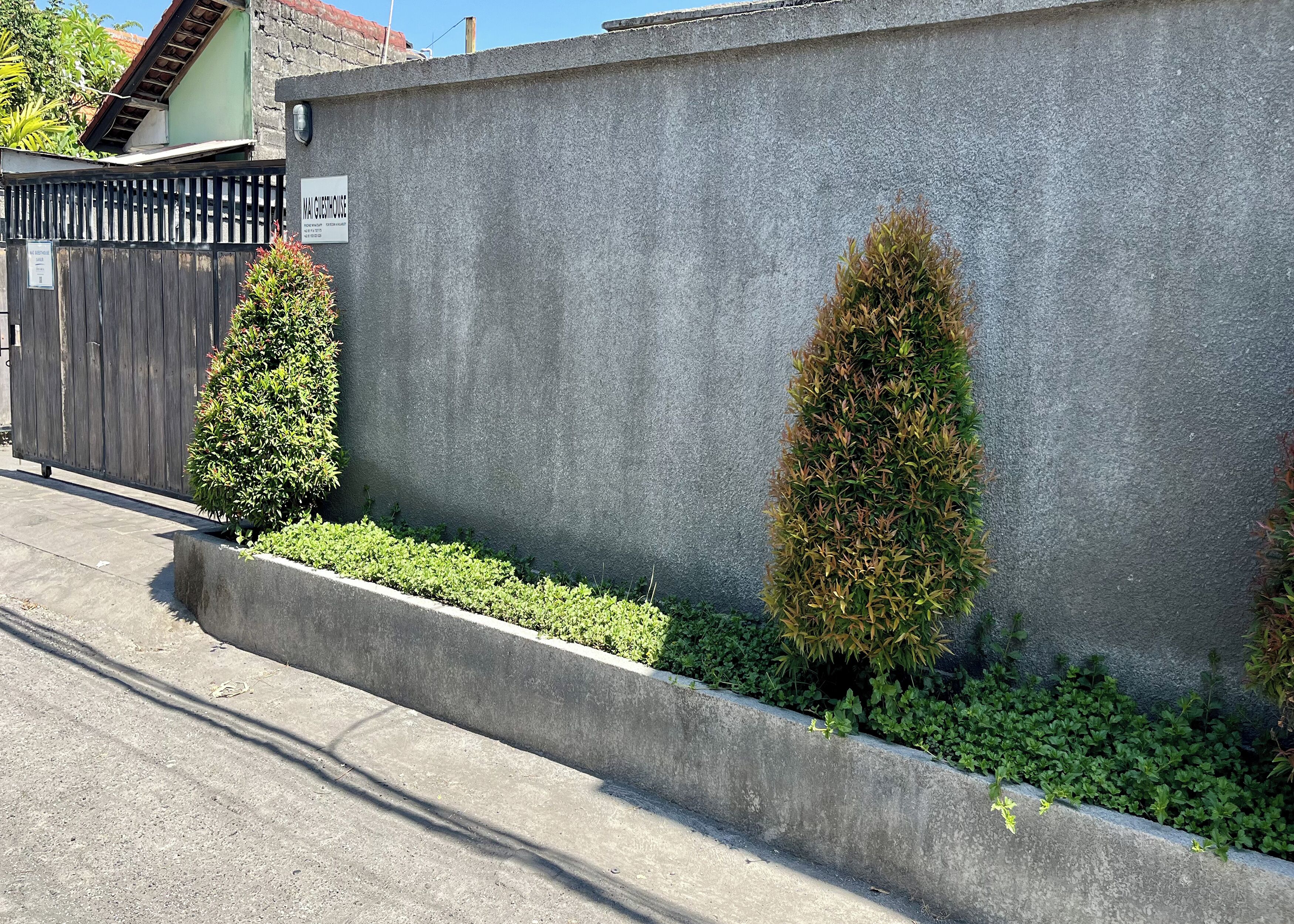 A concrete wall with a sign reading "MAIDHOUSE" and a wooden fence.