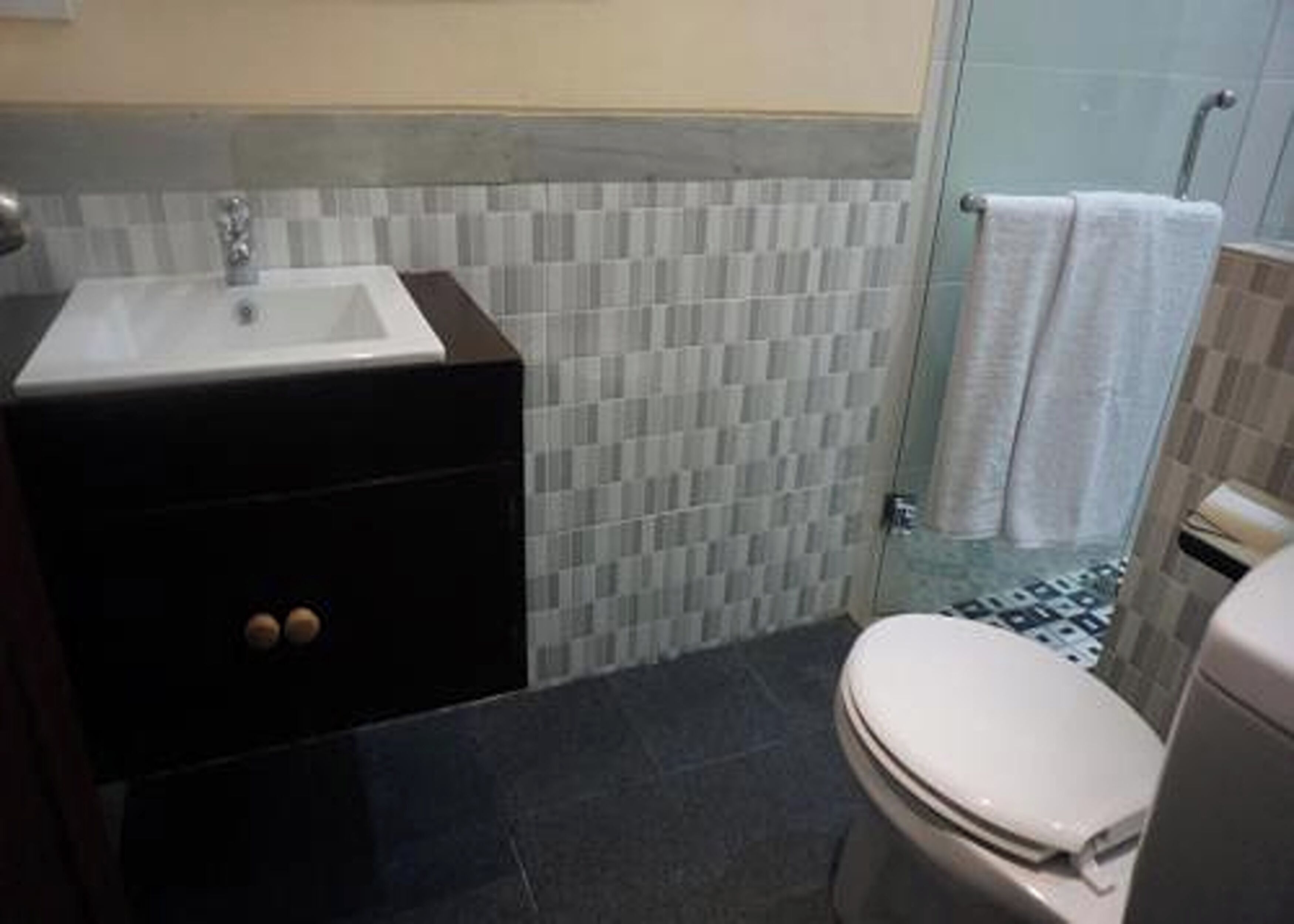 A bathroom with a sink, toilet, and shower area.