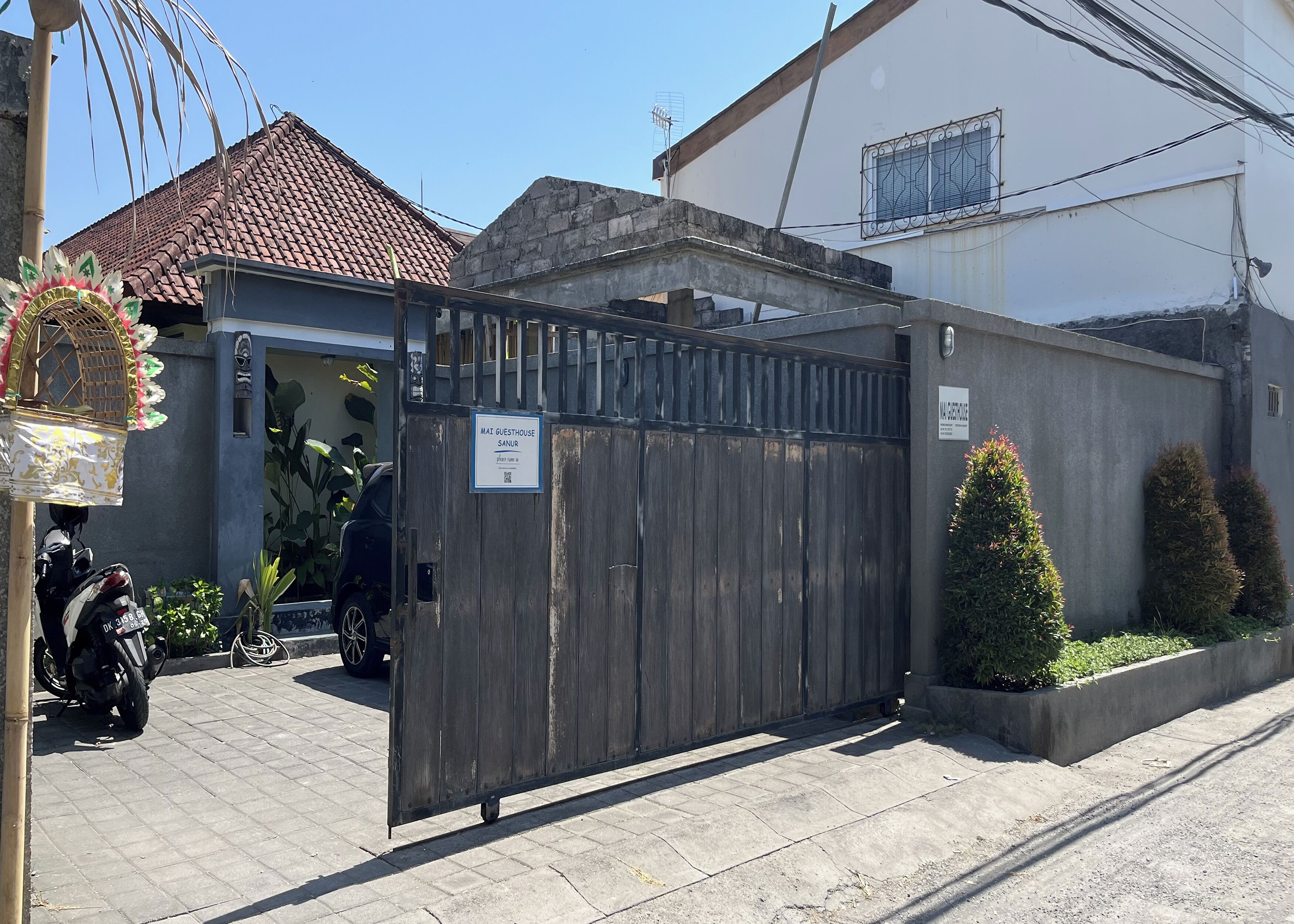 A gated guesthouse with a sign indicating it is a guesthouse.