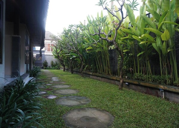 A pathway with stepping stones leading to a building with a covered porch. - Mai Guesthouse Sanur (Denpasar)