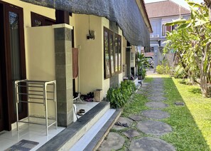 A house with a tiled porch, a metal chair, and a stone pathway leading to the entrance. - Mai Guesthouse Sanur (Denpasar)