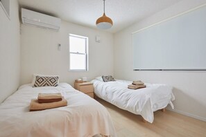 A bedroom with two beds, a window, an air conditioning unit, and a pendant light. - Kasai Guest House, 4min to Kasai Sta, Direct buses to Airport & Disney (Tokyo)
