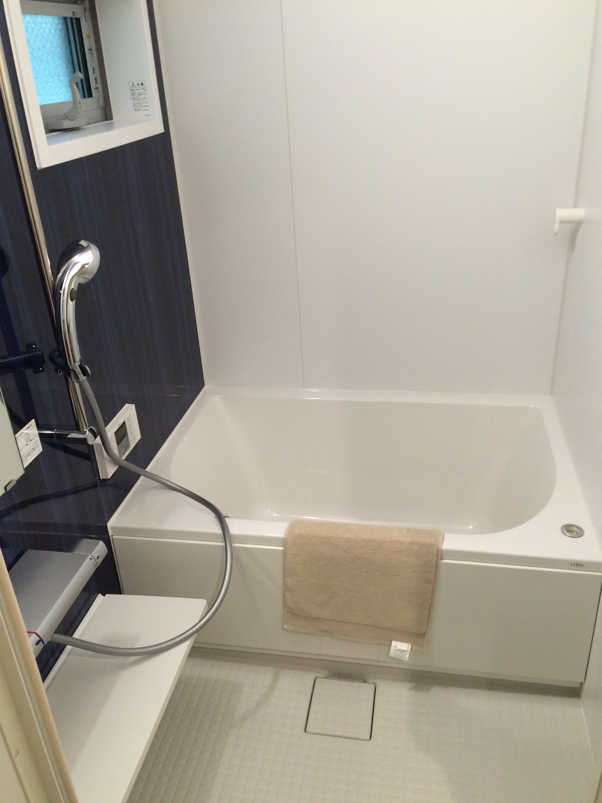 A bathroom with a bathtub, a towel hanging on the side, and a mirror above the sink.