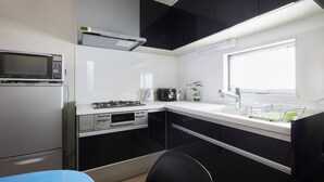 Uma cozinha compacta equipada com micro-ondas, fogão, forno e uma janela que permite a entrada de luz natural.
