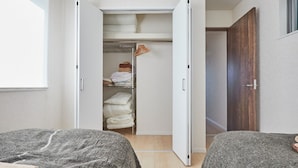 Quarto com duas camas, um guarda-roupa e um armário.