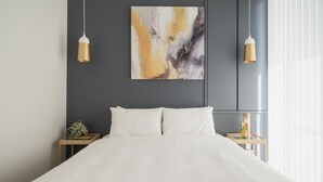 A modern bedroom with a large bed, two bedside tables, a wall-mounted abstract painting, and two pendant lights. - Infinity Hotel -Higawa- (Naha)