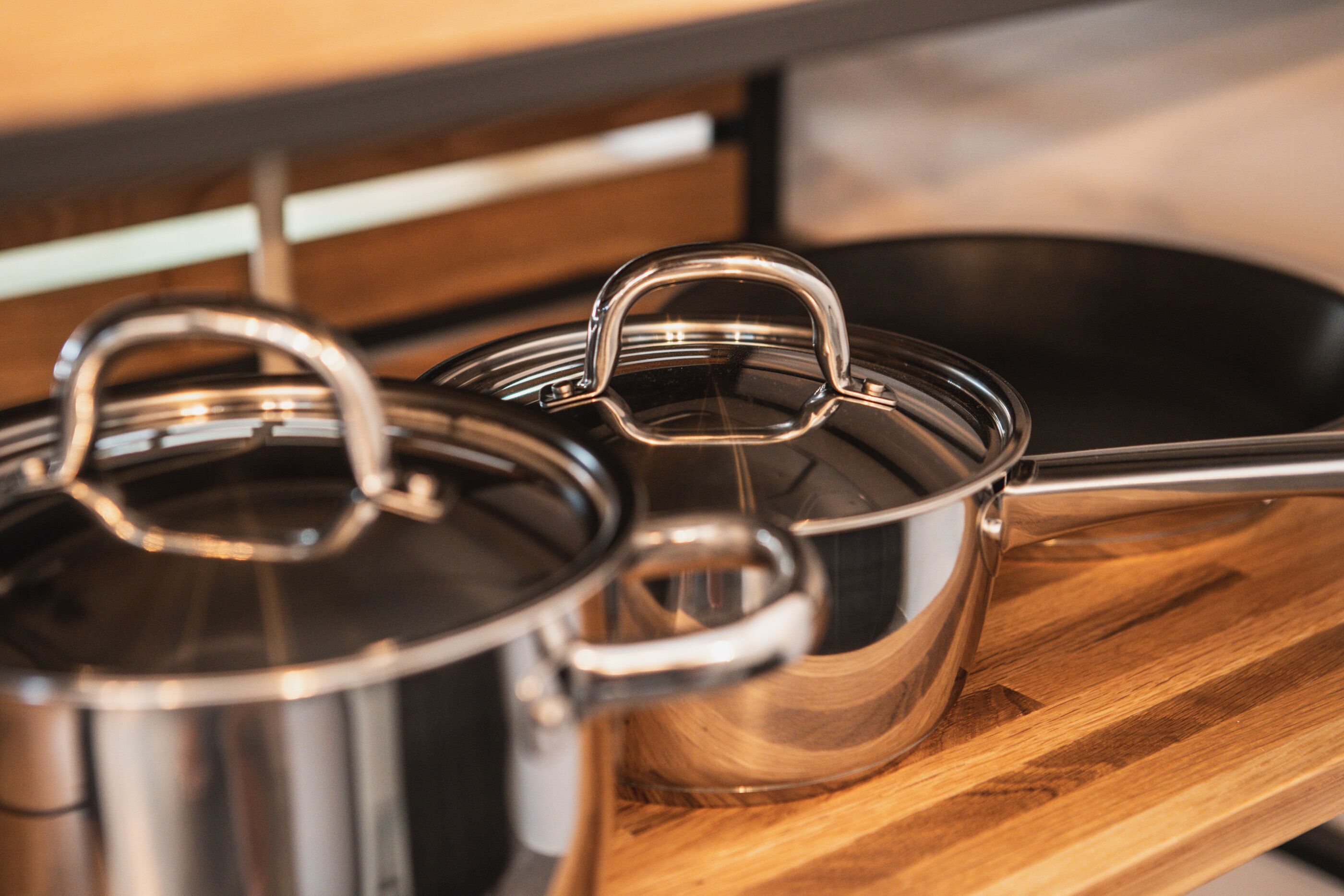 Stainless steel pots with lids on a wooden surface.
