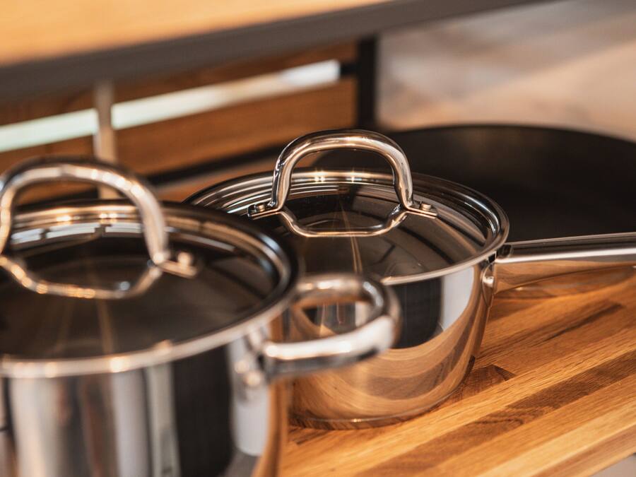 Stainless steel pots with lids on a wooden surface.