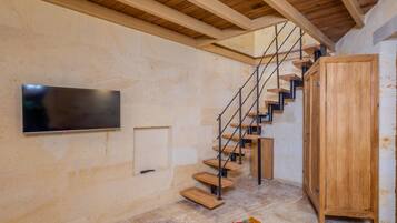 Una escalera con escalones de madera y barandillas metálicas, un armario de madera y un televisor de pantalla plana montado en la pared.