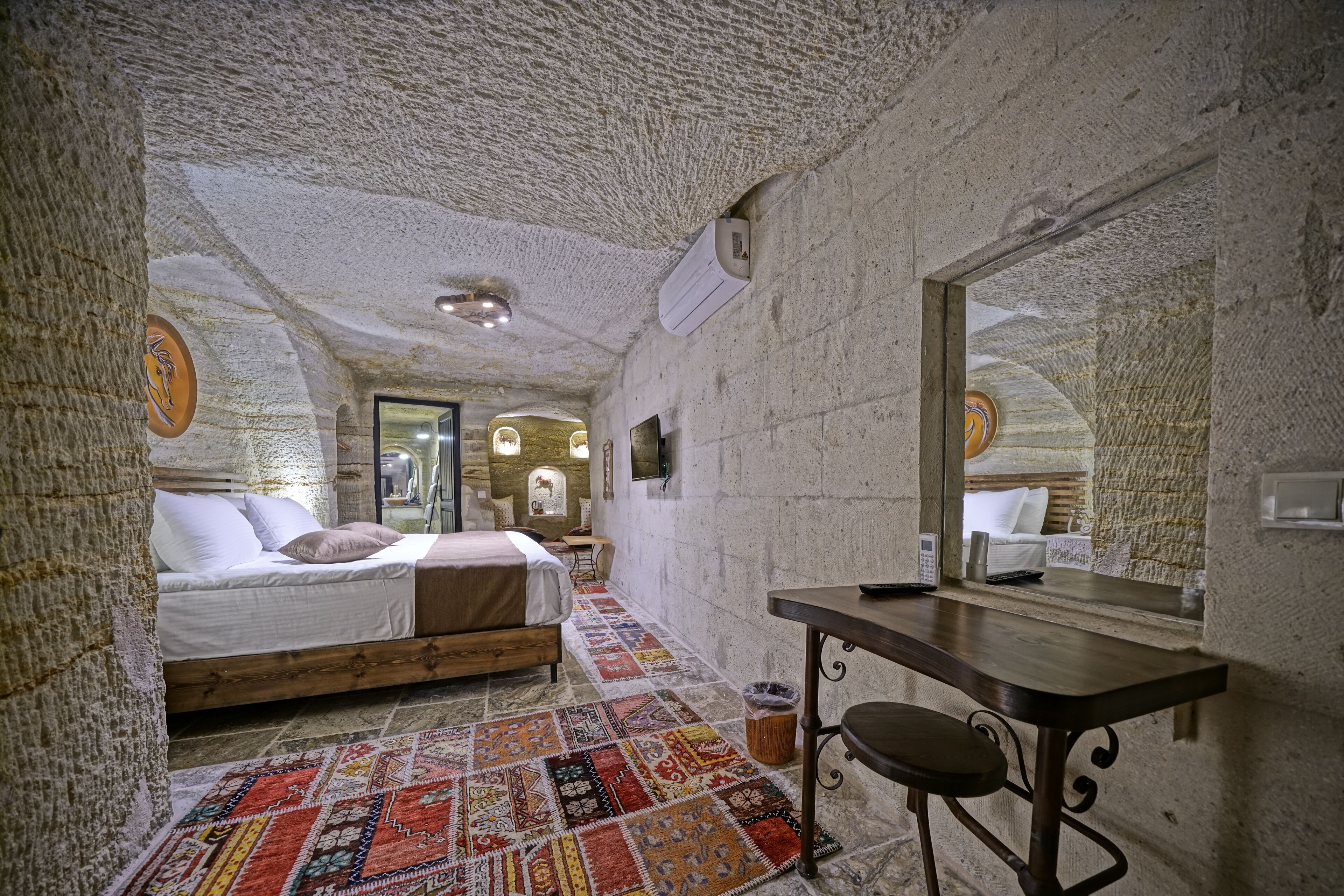 Un dormitorio con cama, escritorio y espejo.