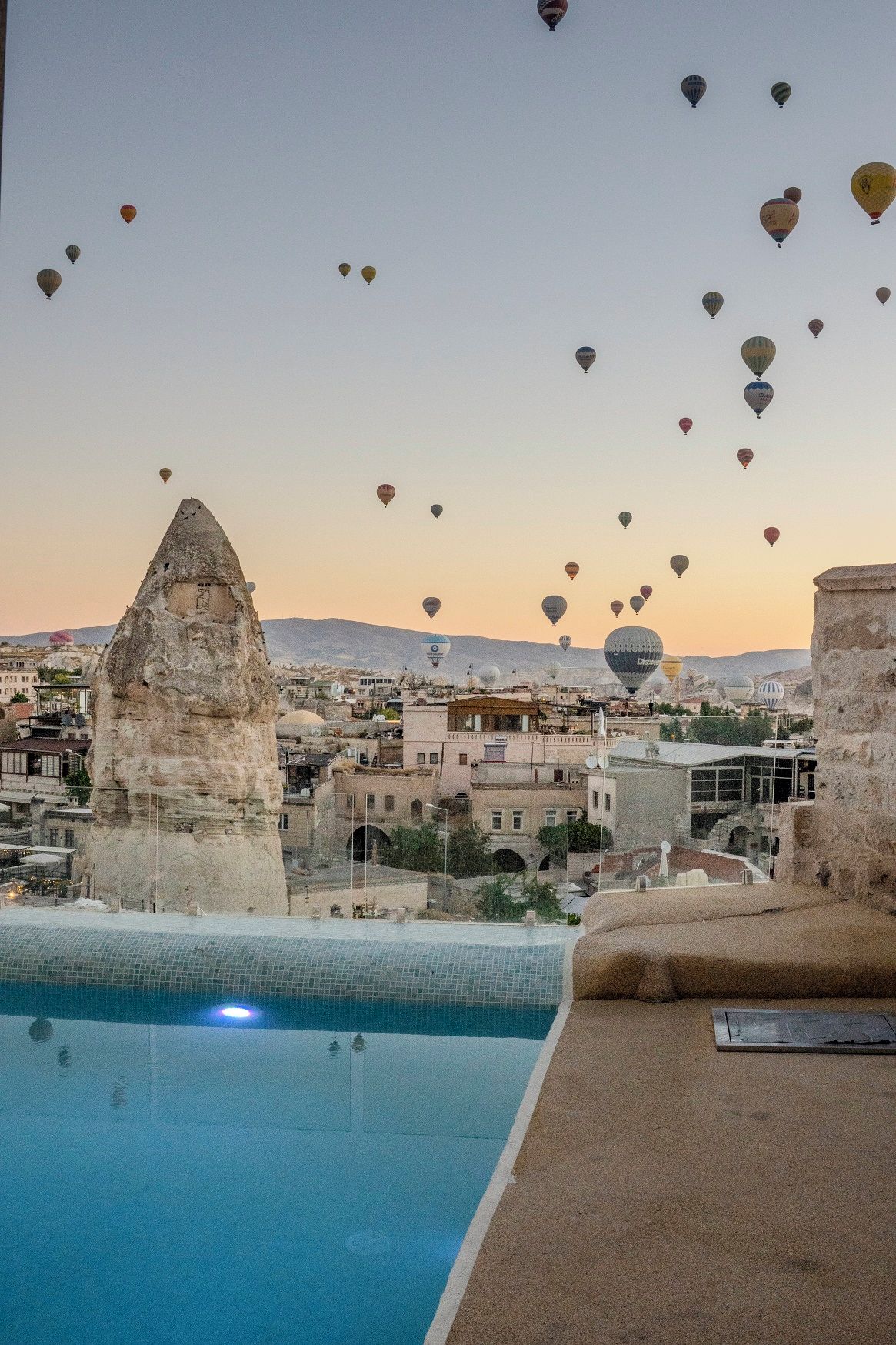 Un espace piscine offrant une vue sur la ville et une formation rocheuse remarquable.