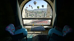 A room with a view of hot air balloons, a table with glasses, and two patterned chairs. - Arinna Cappadocia (Nevsehir)