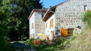 A stone building with a gravel path leading to it, surrounded by greenery.