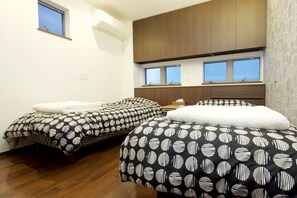 A bedroom with two beds, wooden cabinets, a window, and a small table.