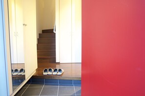 Un corridoio con una scala in legno, un pavimento piastrellato e un paio di scarpe sui gradini.