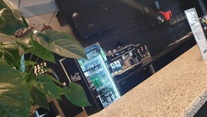 A bar area with a granite countertop, a potted plant, and a Coca-Cola refrigerator. - Hotell Pausa (Klippan)