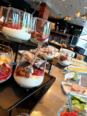 A buffet with various dishes, including yogurt parfaits and fresh vegetables. - Hotell Pausa (Klippan)