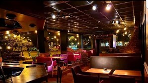 An indoor restaurant with booths and tables, a brick wall, and hanging lights. - Hotell Pausa (Klippan)