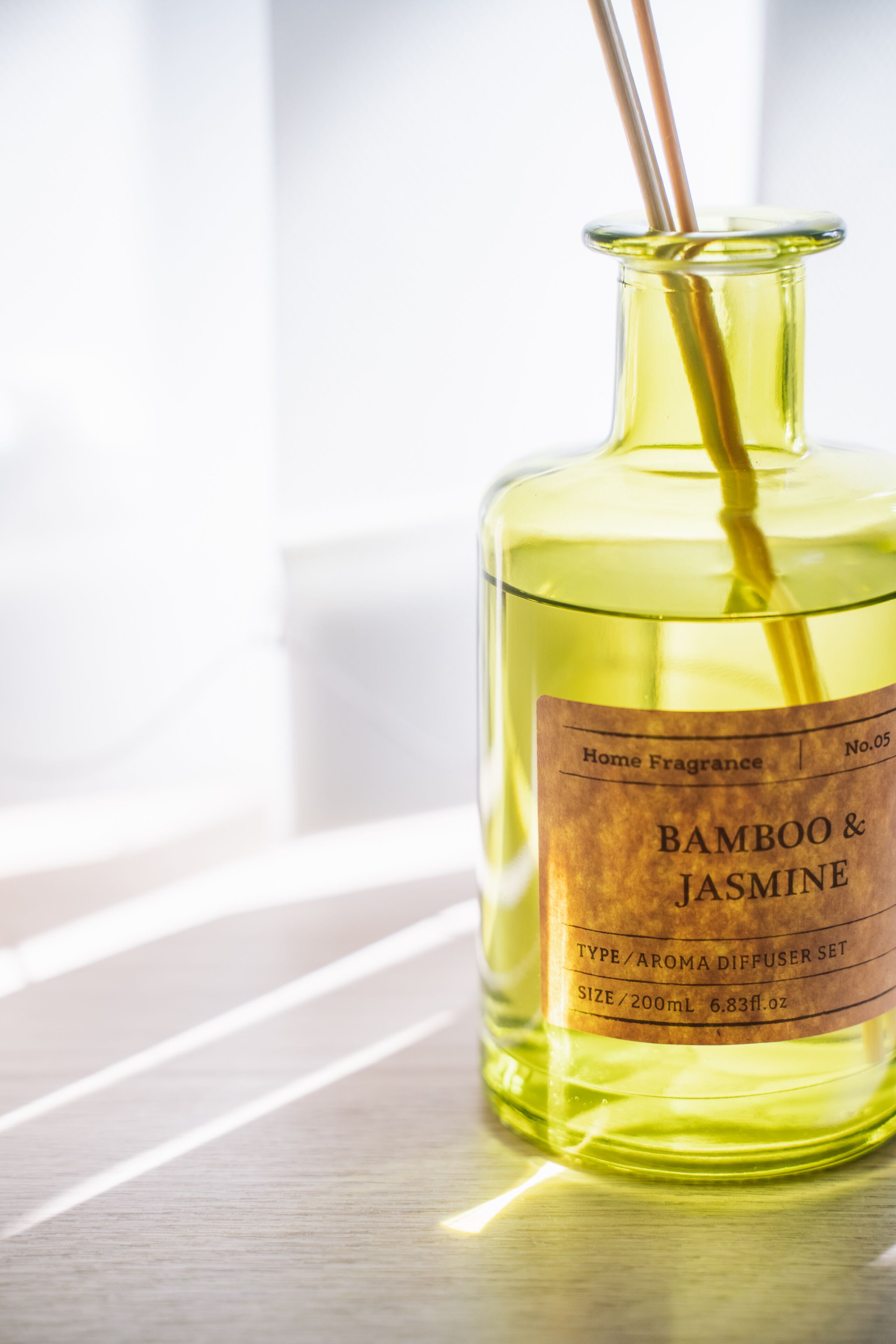 A bottle of 'Bamboo & Jasmine' home fragrance diffuser set on a wooden surface.