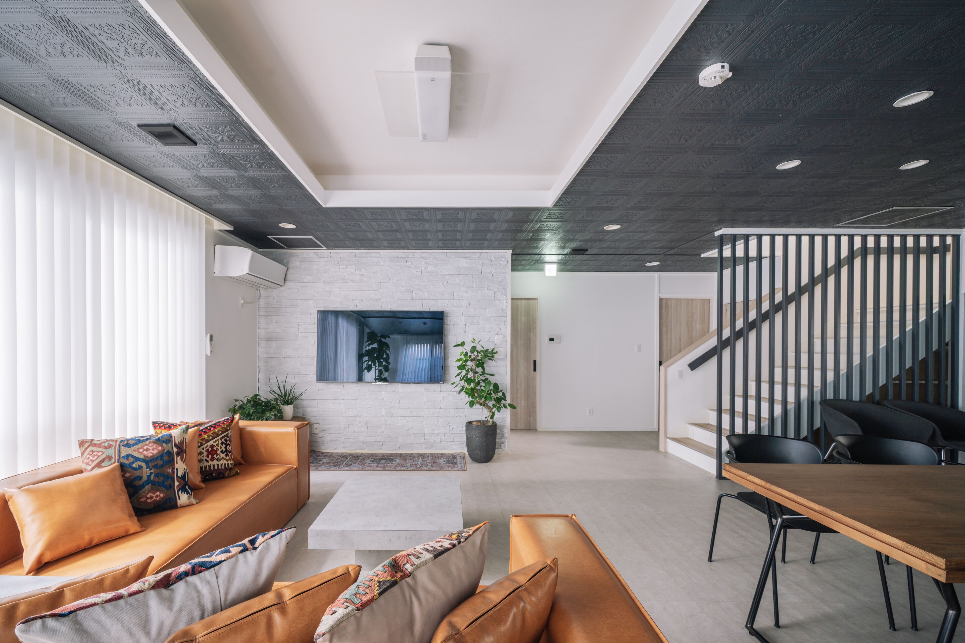Una sala de estar moderna con un sofá, una mesa de centro y un comedor con una mesa y sillas de madera.