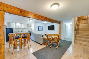 Cozy dining area with a round table and four chairs, a comfortable rocking chair, and a fully equipped kitchen in the background.