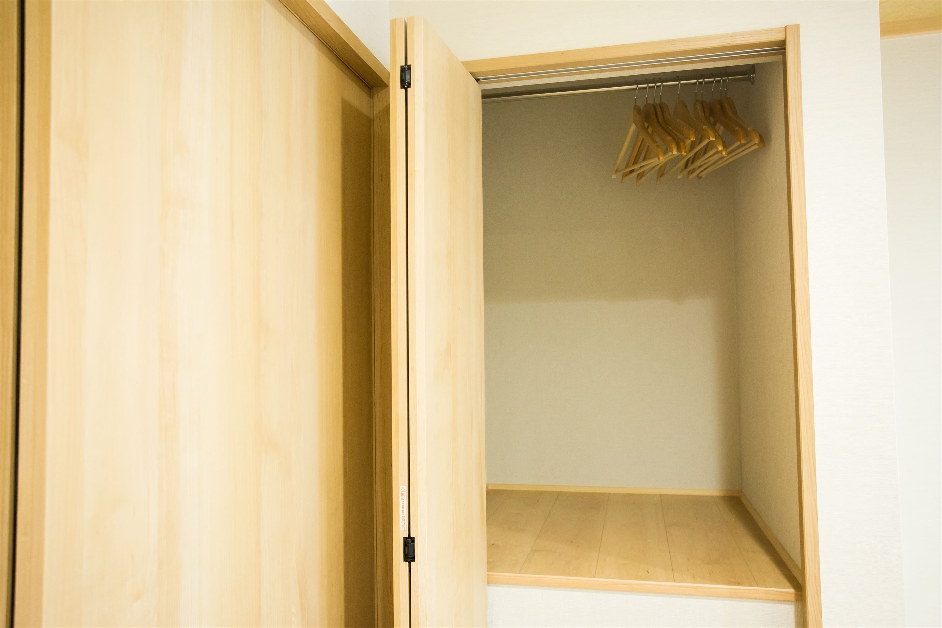 Un placard en bois avec une tringle pour suspendre les vêtements et un porte-chaussures.