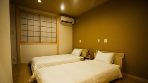 A hotel room with two beds, a wooden floor, a window with a view, and an air conditioning unit. - Oyado Toshi (Kyoto)