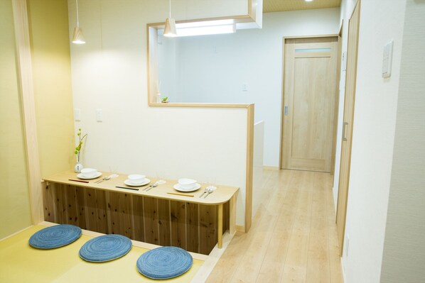 A dining area with a wooden table set for four, a mirror above, and a wooden door in the background.