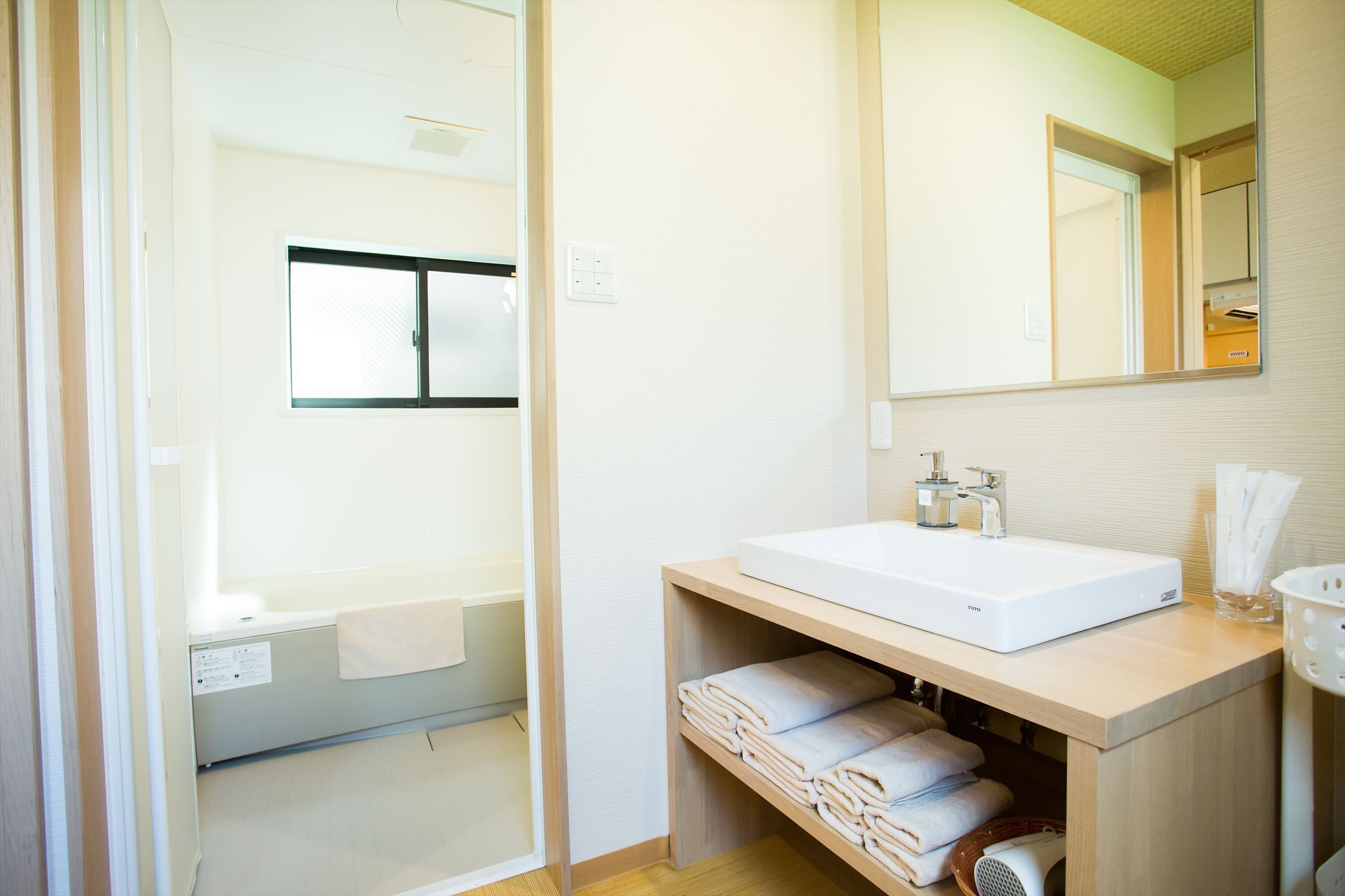 Un baño moderno con un lavamanos grande de color blanco, un espejo y una zona de ducha.