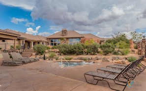 A resort with a pool, lounge chairs, and a stone building with a large window.