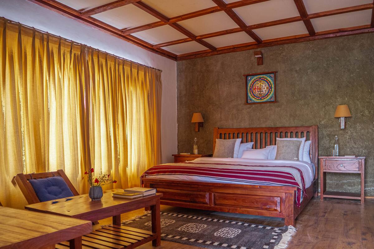 A room with a wooden bed, a wooden desk, a chair, a table, a lamp, and a rug.
