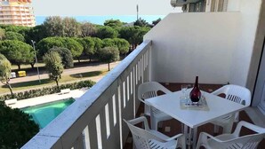 A balcony with a white table and four white chairs, overlooking a swimming pool and greenery. - Holiday apartment mit Pool (Porto Santa Margherita)