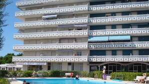 A multi-story hotel with balconies, a swimming pool, and a sign for a restaurant. - Holiday apartment mit Pool (Porto Santa Margherita)