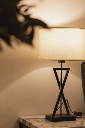 Eine moderne Stehlampe mit geometrischer Basis und Stoffschirm, auf einer Marmorplatte vor einer schlichten Wand platziert.