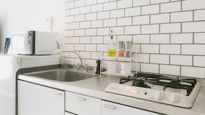 A kitchen with white cabinets, a stainless steel sink, a gas stove, and a microwave. - Akebono 5-C (Naha)