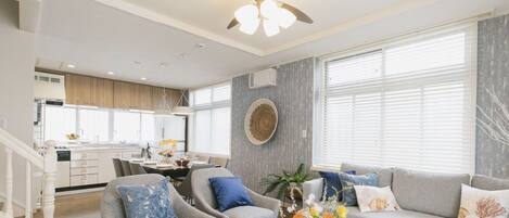 A modern living room with a sofa, armchairs, and a dining area.