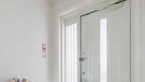 A white door with a handle and a lock, a white cabinet with a small shelf, and a tiled floor. - Sunset Breeze Chatan  (Chatan)
