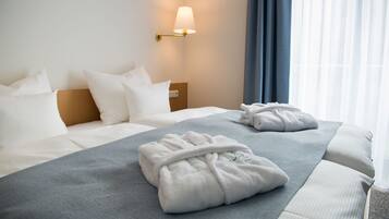 A hotel room with a neatly made bed, a bedside lamp, and a view of the window with curtains.