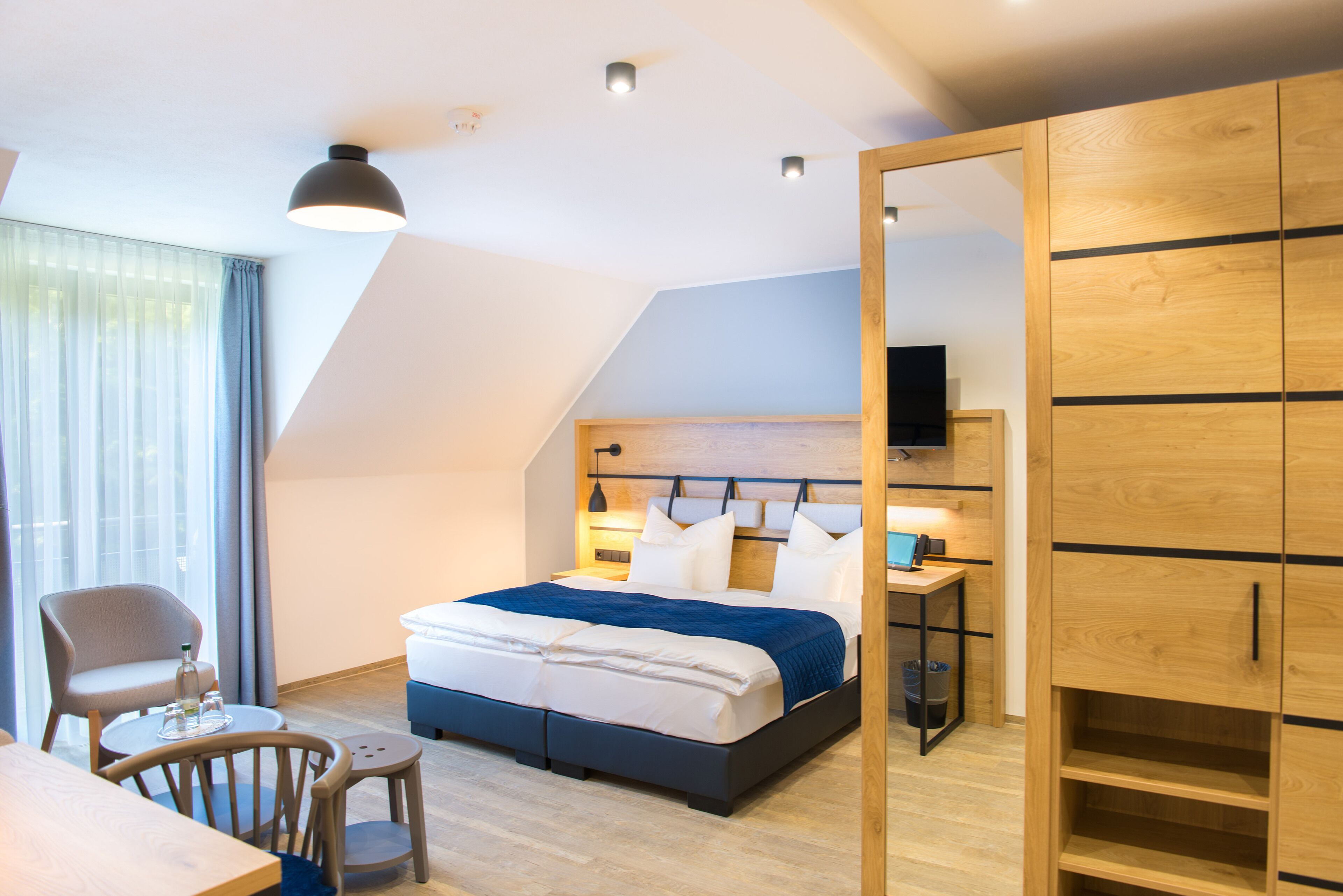 Un dormitorio moderno con cama, mesita de noche y televisor.