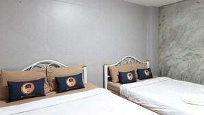 Dos camas con cabeceras y almohadas a juego, un techo blanco y una pared con textura.