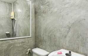 Bathroom features a toilet, sink, and showerhead, with a mirror and door nearby.