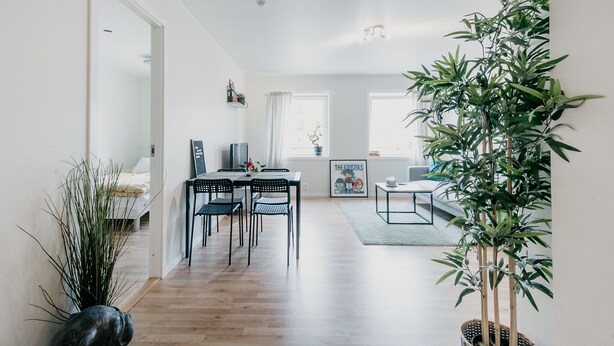 Ett modernt vardagsrum med matplats, kök och ett stort fönster.