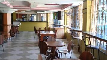A restaurant with checkered flooring, wooden tables and chairs, and a red and white ceiling design.