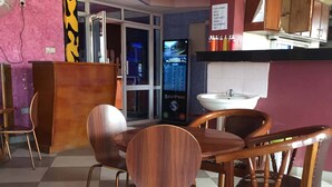 A restaurant interior with a checkered floor, wooden chairs, a counter, and a digital menu display. - Checkpoint Inn (Mombasa)