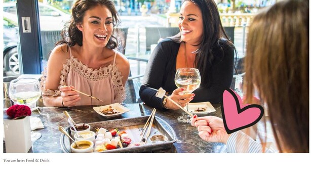 Une table à manger avec de la nourriture et des boissons, notamment un plateau contenant divers plats et un verre de vin.
