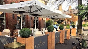 Espace extérieur aménagé avec des parasols, des jardinières en bois et une enseigne indiquant la présence d’une boutique de vins.