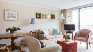 Un salon comprenant un canapé, des fauteuils, une table basse, un téléviseur et un balcon avec vue.