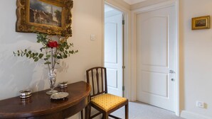 Un coin repas avec une table en bois, une chaise, un vase de fleurs et un tableau encadré au mur.