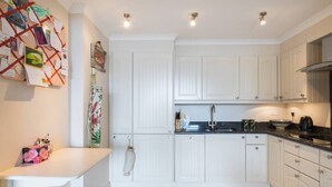Une cuisine moderne avec des meubles blancs, un plan de travail noir et un porte-ustensiles suspendu.