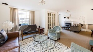 Uma sala de estar com sofá, poltronas, mesa de centro e lareira.